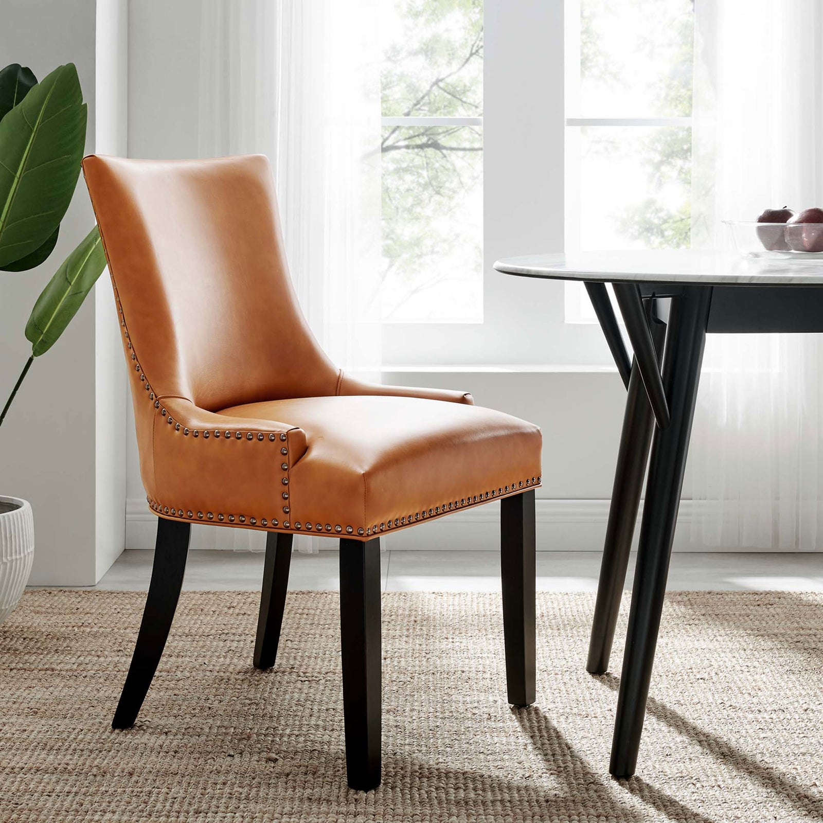 Tan vegan leather dining chair styled by a round dining table in a bright modern room || EEI-2228-TAN || front_angle_room