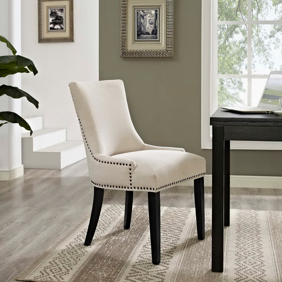 Beige upholstery and nailhead trim lend warmth to a cushioned dining chair with tapered dark legs