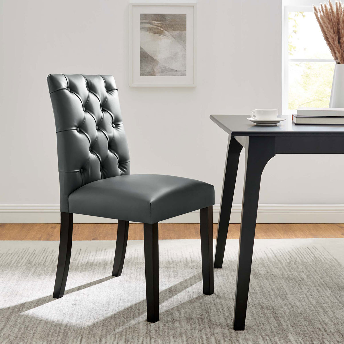 Gray tufted dining chair paired with a sleek black table in a bright contemporary dining room || EEI-2230-GRY || front_angle_room