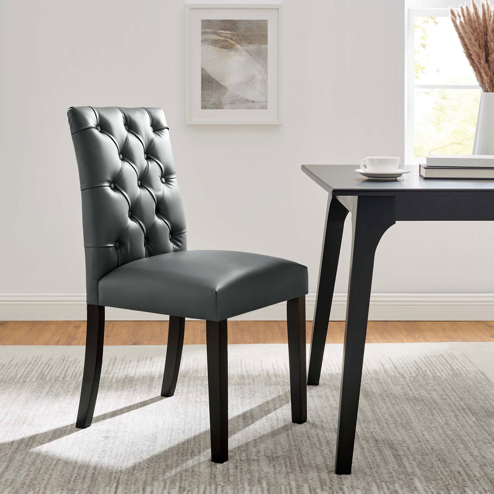 Gray tufted dining chair paired with a sleek black table in a bright contemporary dining room || EEI-2230-GRY || front_angle_room