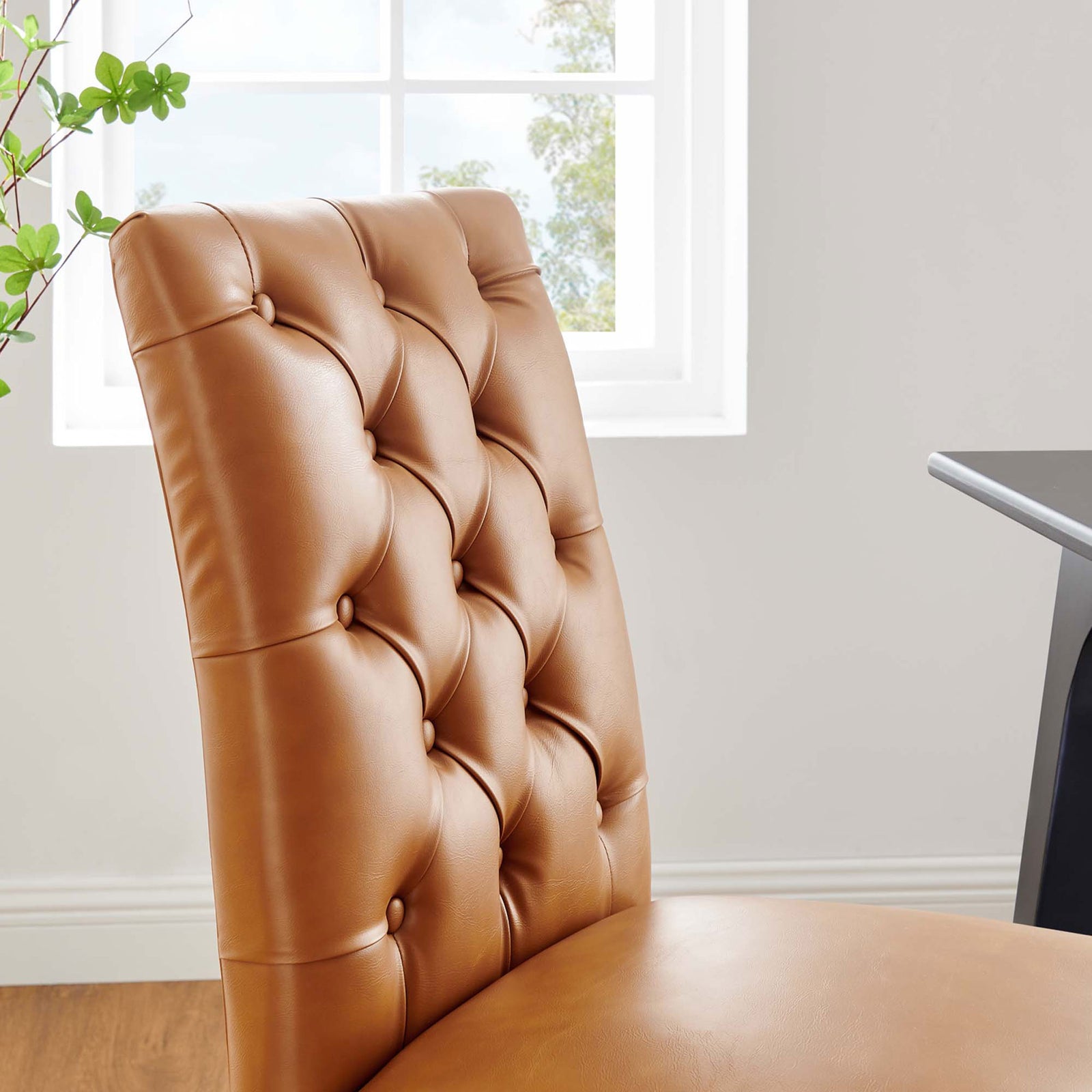 Sunlit close-up of the tan tufted backrest showcasing the chair's soft curves and rich vegan leather. || EEI-2230-TAN || detail_room