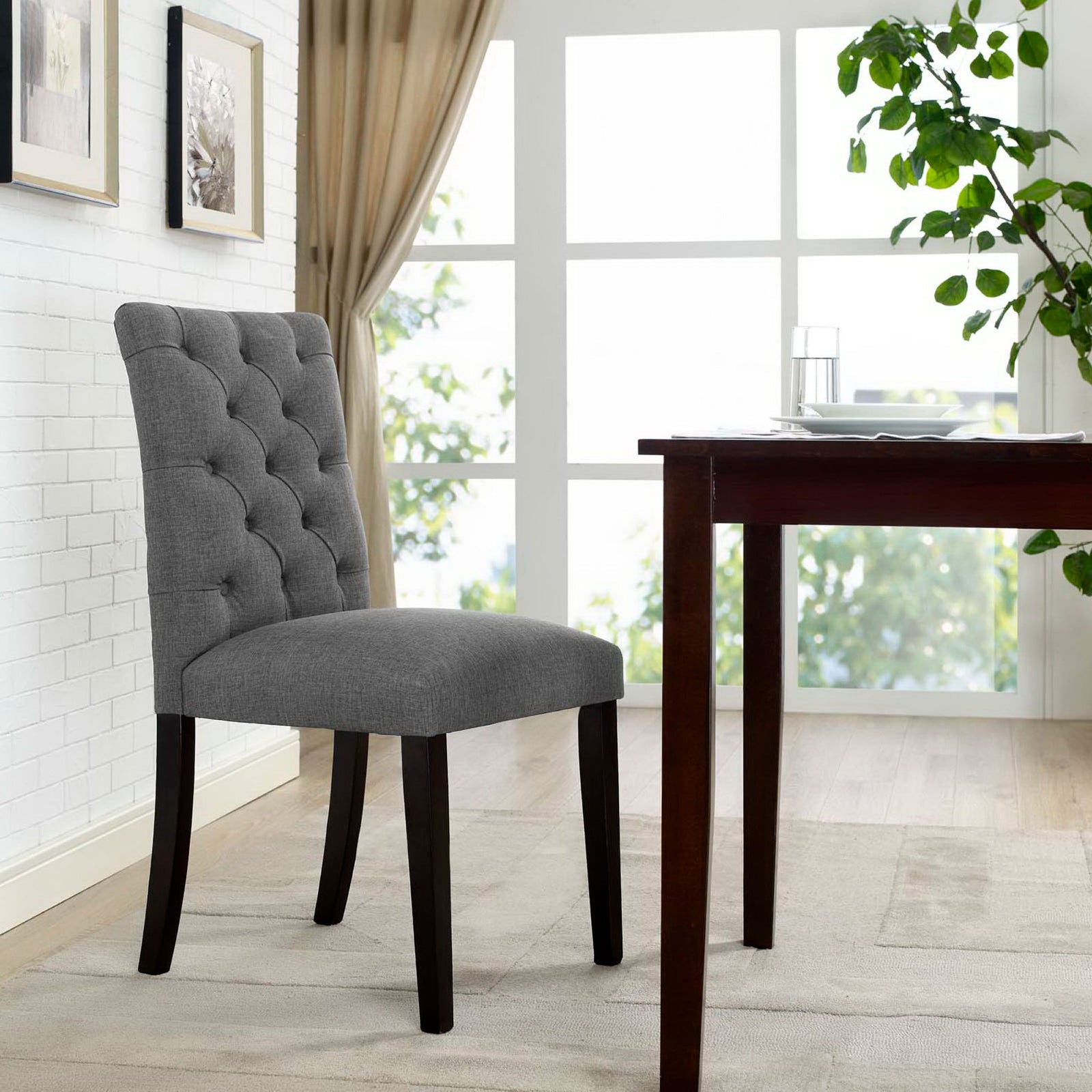Gray tufted dining chair beside a wood table in a bright airy dining room || EEI-2231-GRY || front_angle_room