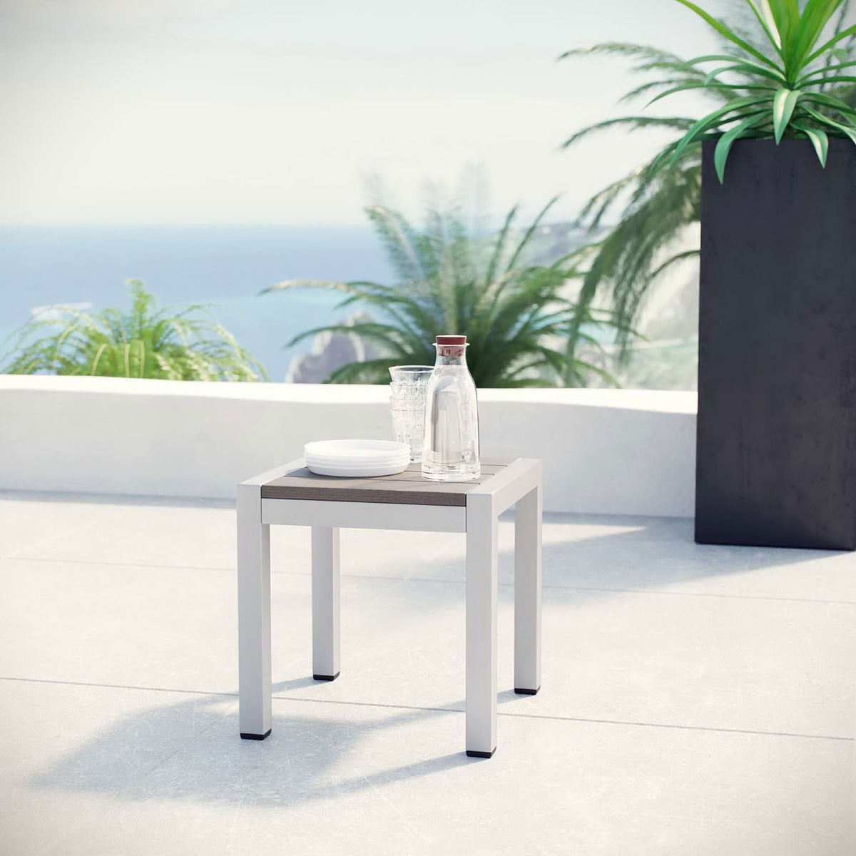 Patio scene with modern silver side table styled with drinks against a coastal backdrop || EEI-2248-SLV-GRY || front_angle_room