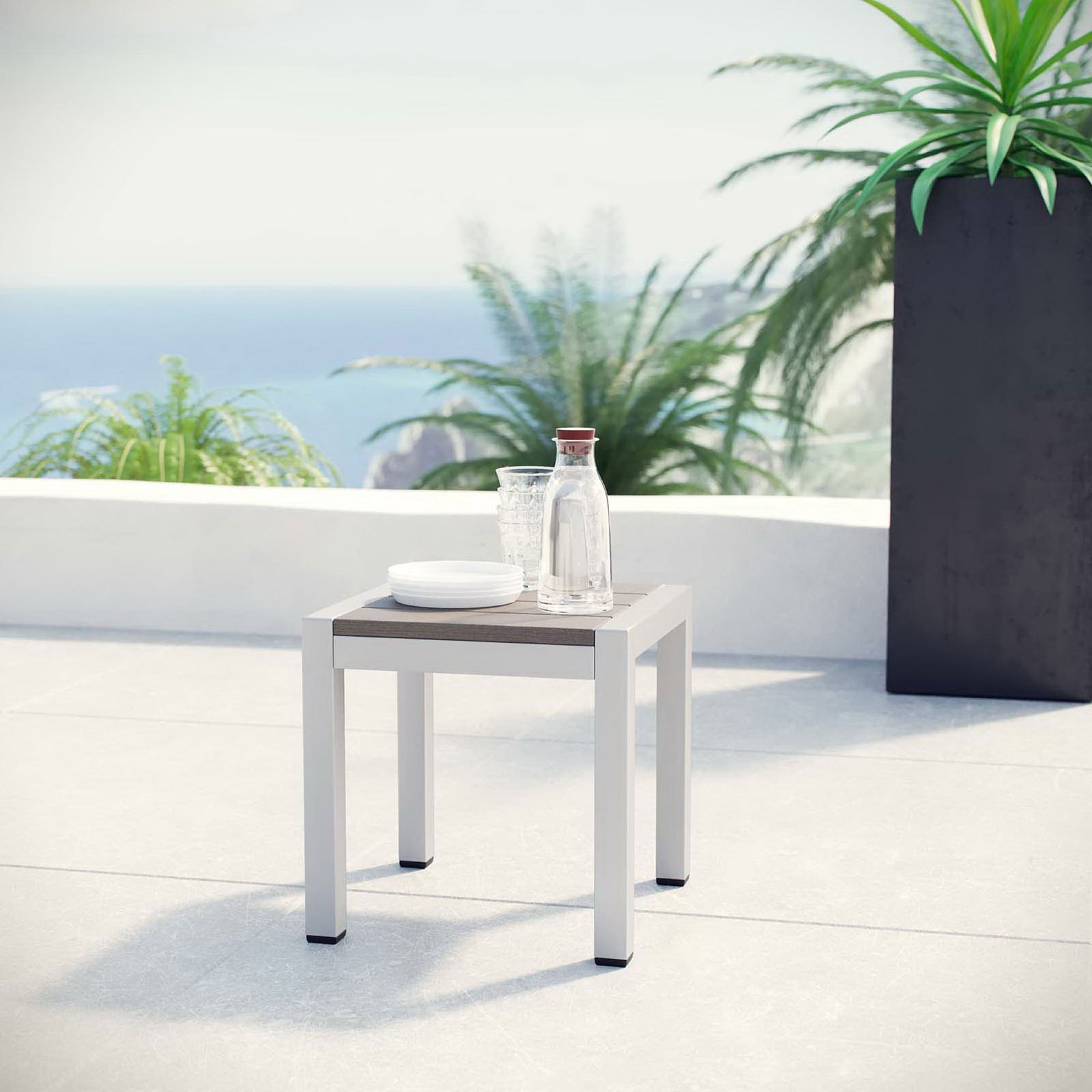 Patio scene with modern silver side table styled with drinks against a coastal backdrop || EEI-2248-SLV-GRY || front_angle_room