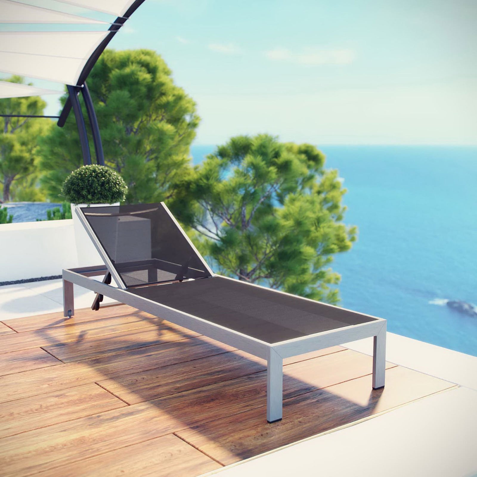 Black mesh Shore chaise resting on a sunny waterfront deck for resort style relaxation || EEI-2249-SLV-BLK || front_angle_room