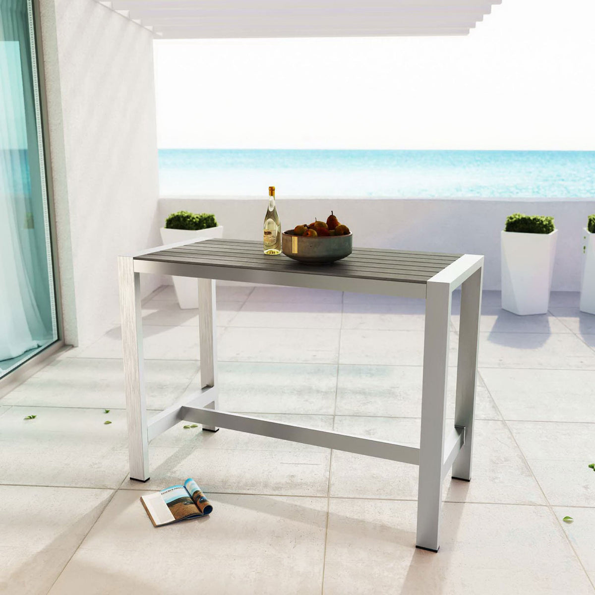 Sleek silver gray bar table styled on a sunny patio with ocean view for modern outdoor entertaining. || EEI-2253-SLV-GRY || front_angle_room