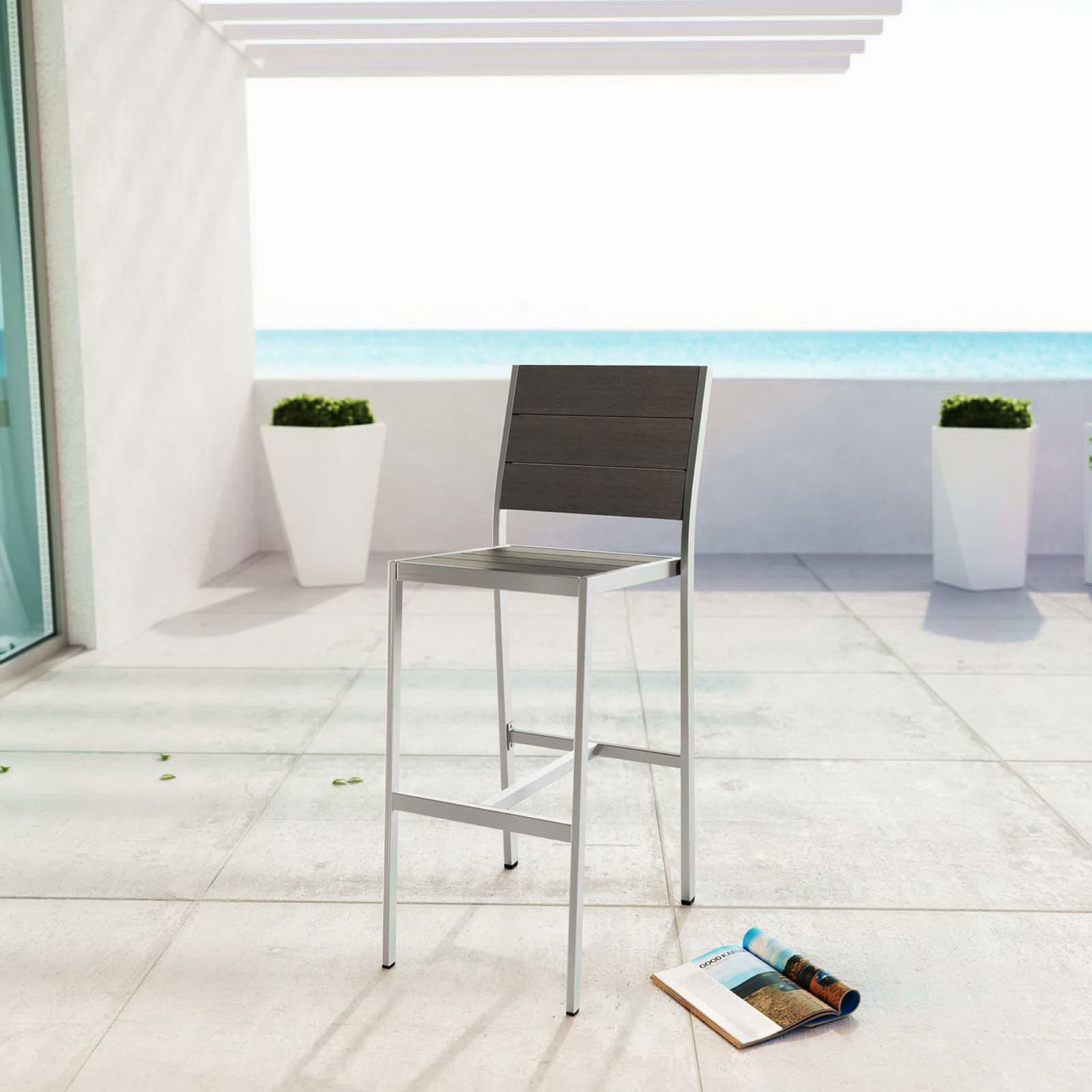 Armless bar stool styled on a sunny oceanfront patio for sleek, contemporary outdoor entertaining || EEI-2255-SLV-GRY || front_angle_room
