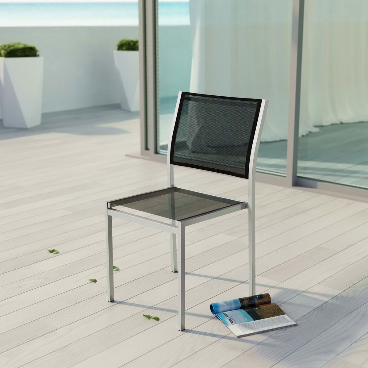 Black mesh Shore side chair adds modern seating to a sunlit oceanside deck. || EEI-2259-SLV-BLK || front_angle_room