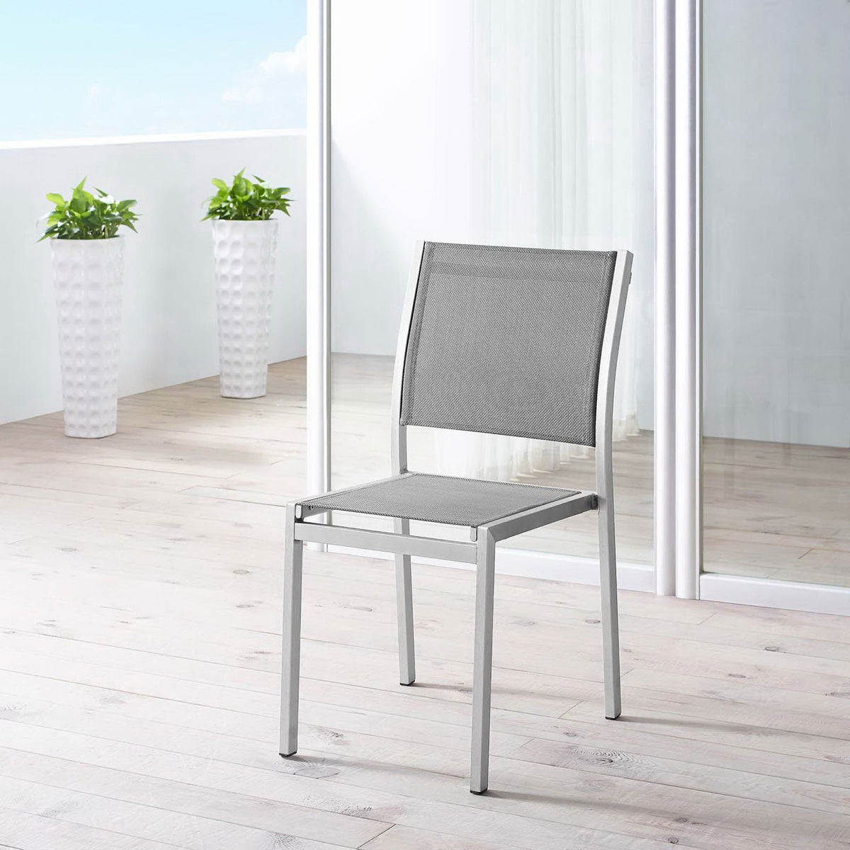 Gray mesh Shore side chair brings airy style to a bright balcony patio setting. || EEI-2259-SLV-GRY || front_angle_room