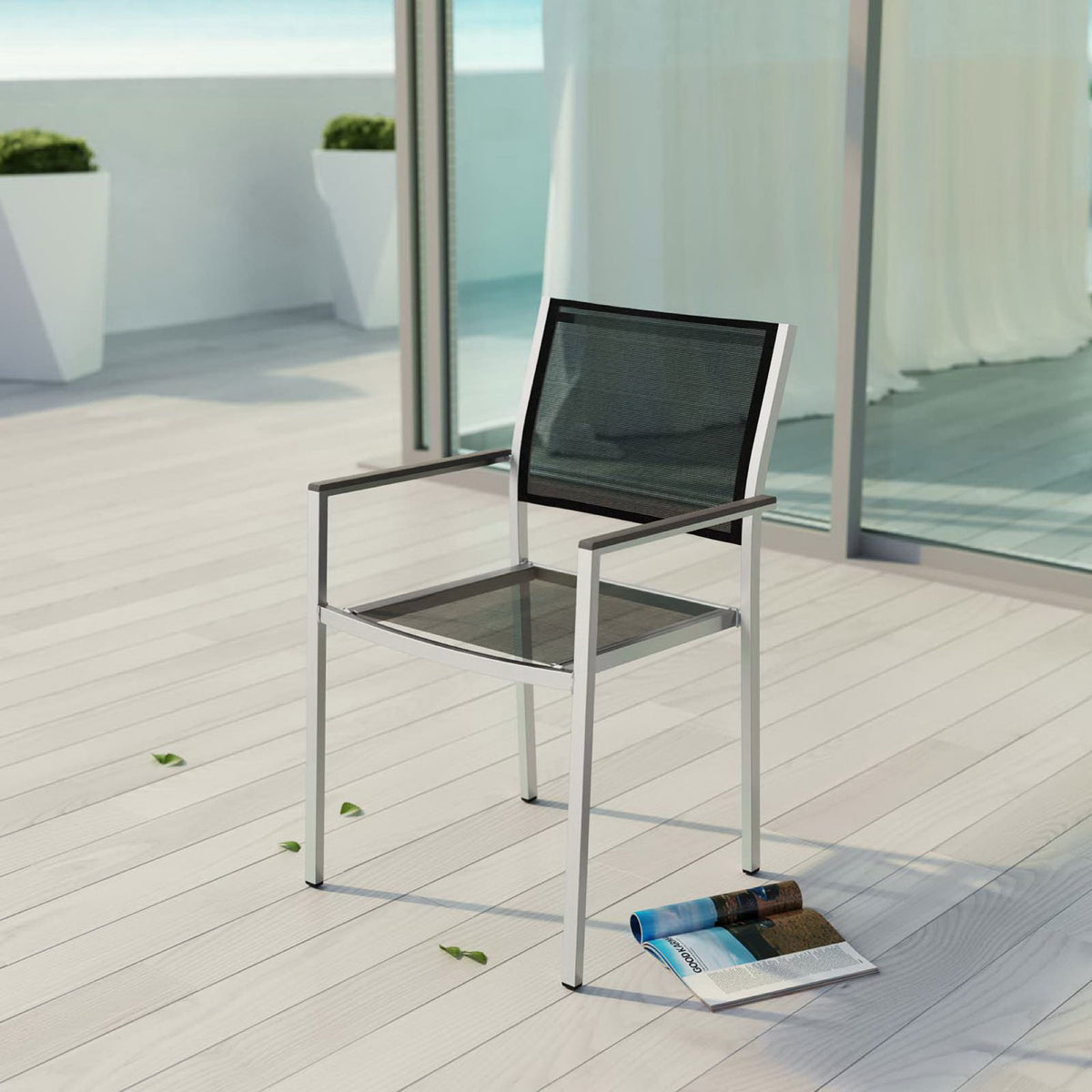 Black mesh Shore armchair adds modern comfort to a bright oceanside patio deck. || EEI-2272-SLV-BLK || front_angle_room