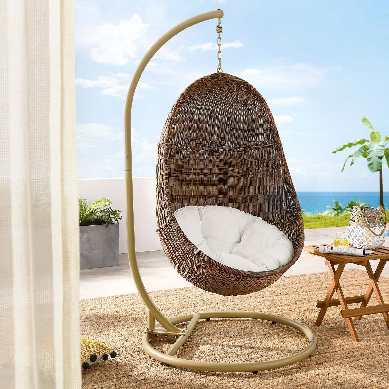 Outdoor egg swing chair with white cushion and tan stand brings resort-style relaxation to a sunny patio || EEI-2277-YLW-WHI-SET || front_angle_room