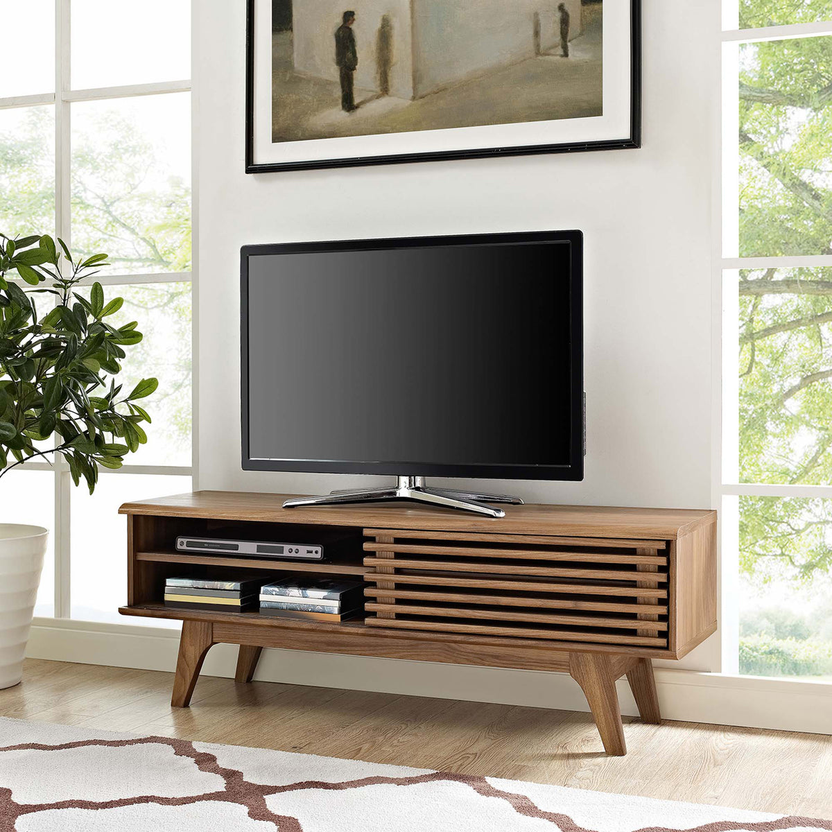Walnut TV stand in a bright living room holding TV and electronics with rug and wall art accents