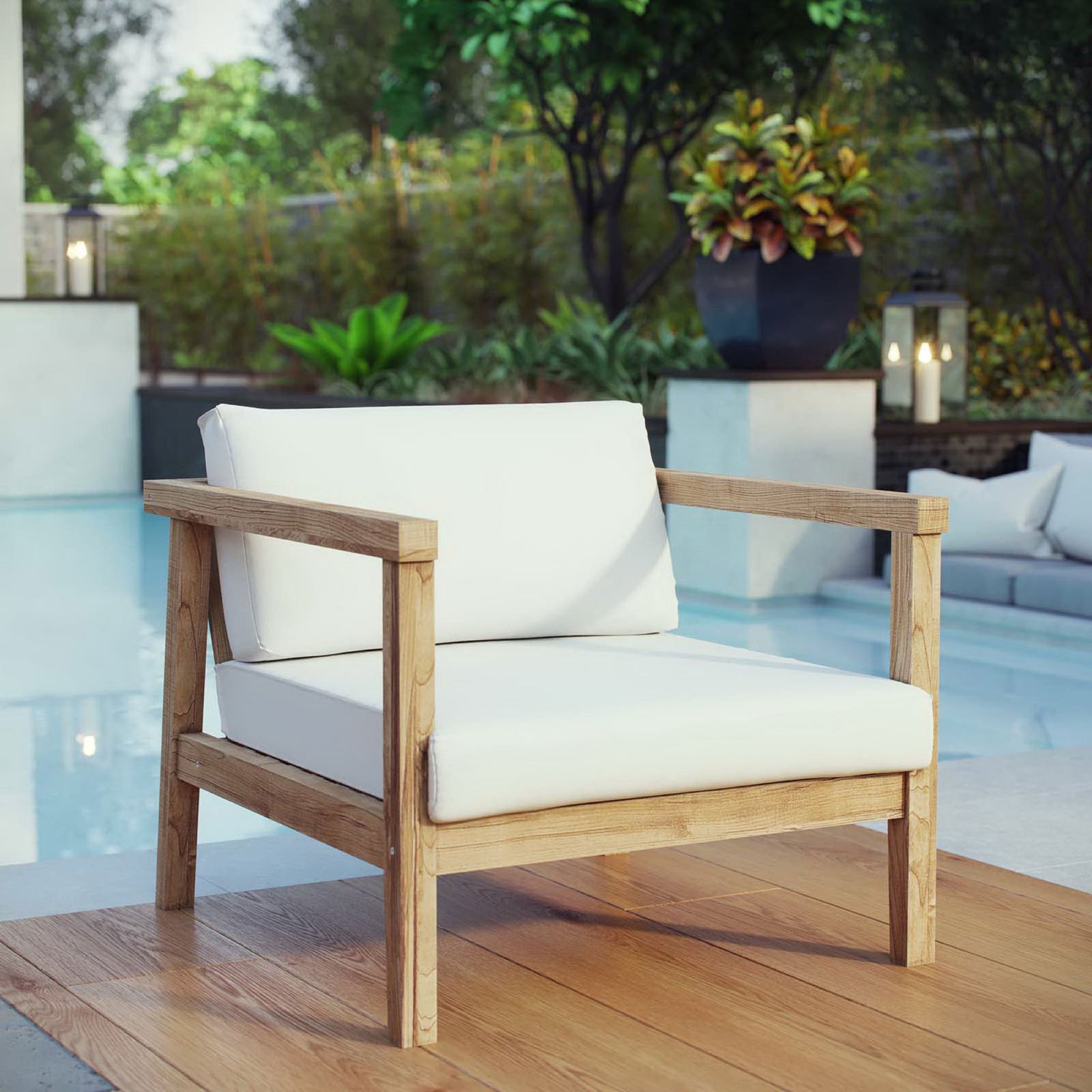 Poolside teak armchair with clean-lined frame and weather-ready white cushions on a warm wood deck || EEI-2695-NAT-WHI || front_angle_room