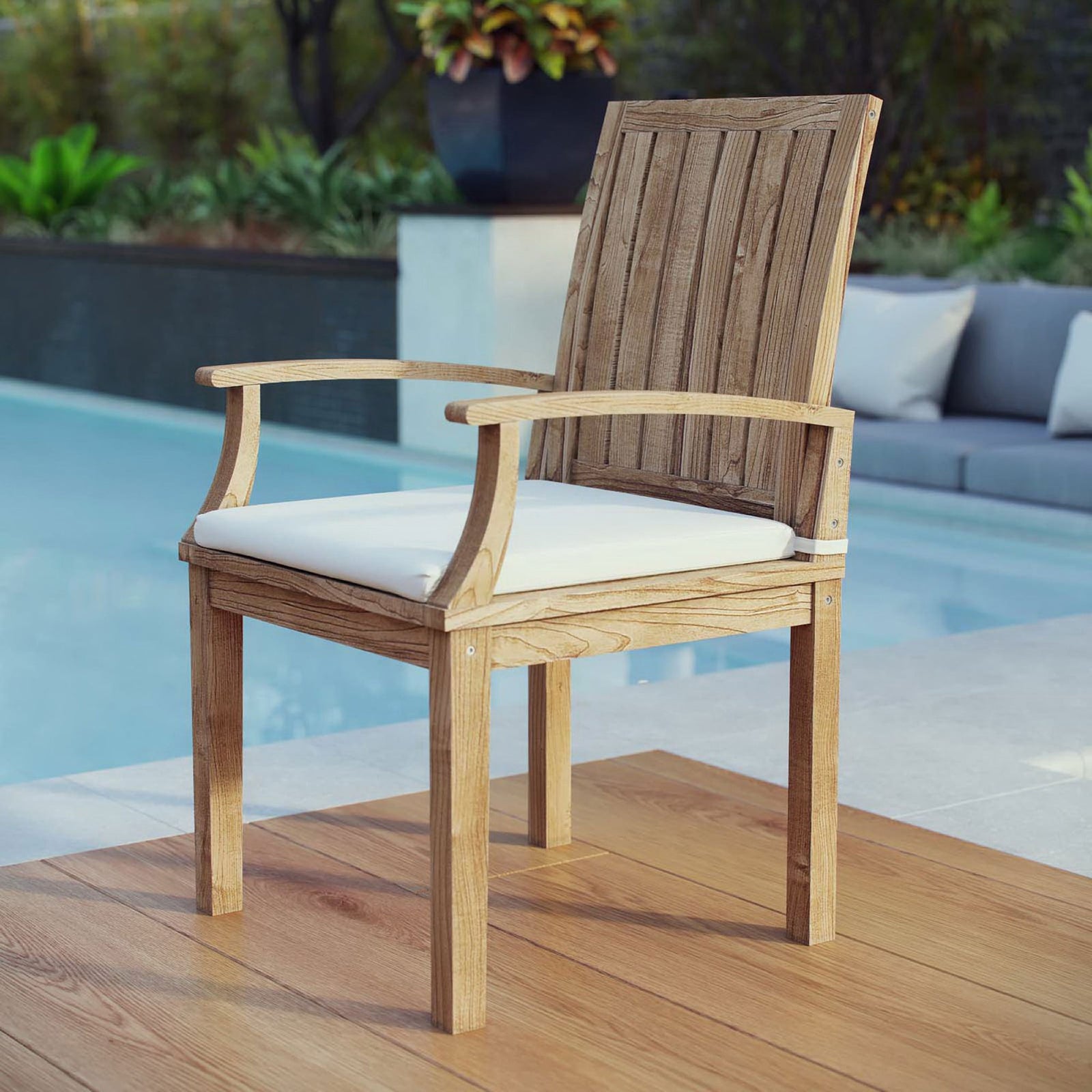 Teak armchair with white cushion styled beside a modern pool for relaxed outdoor dining || EEI-2701-NAT-WHI || front_angle_room
