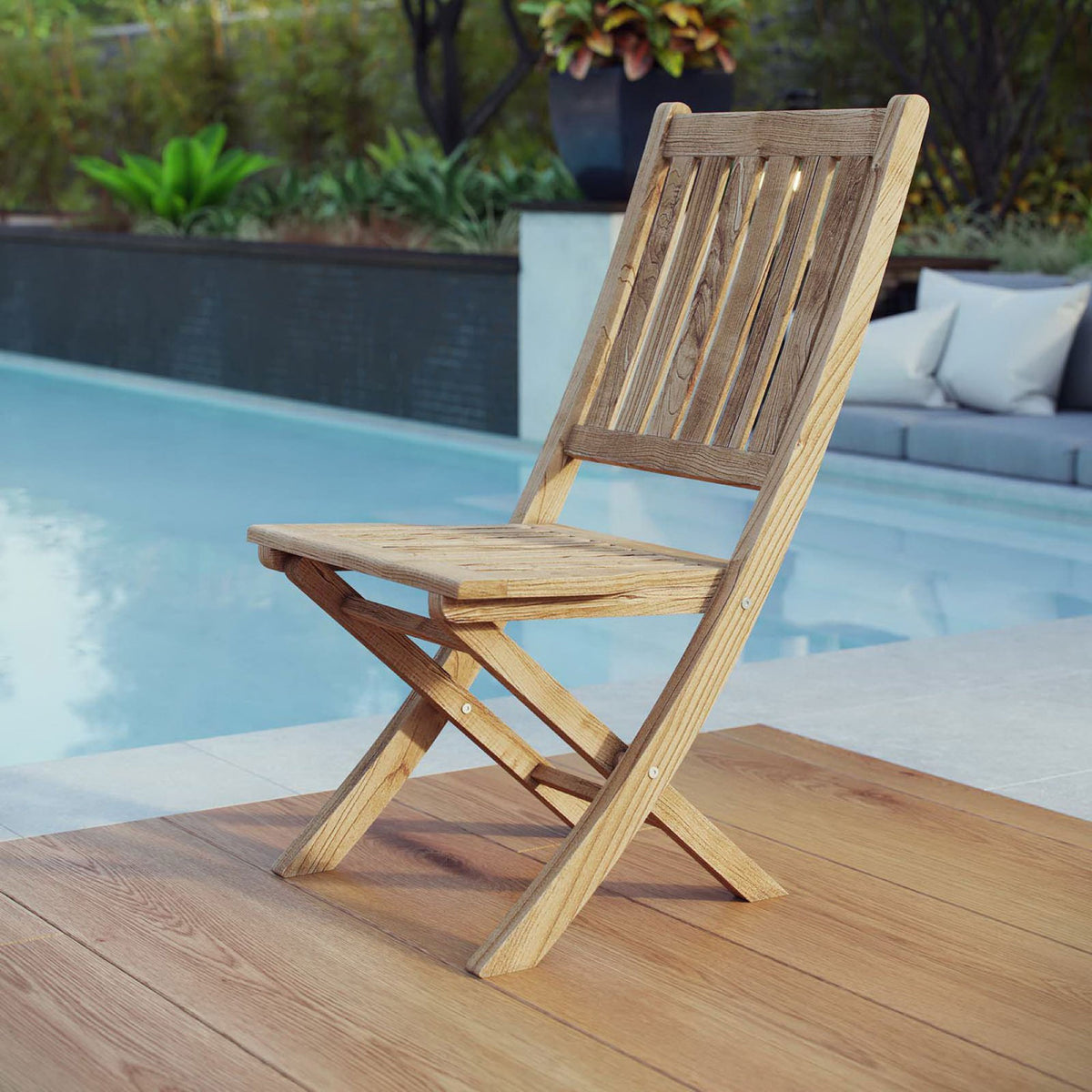 Teak folding side chair arranged on a poolside deck for flexible outdoor seating || EEI-2702-NAT || front_angle_room