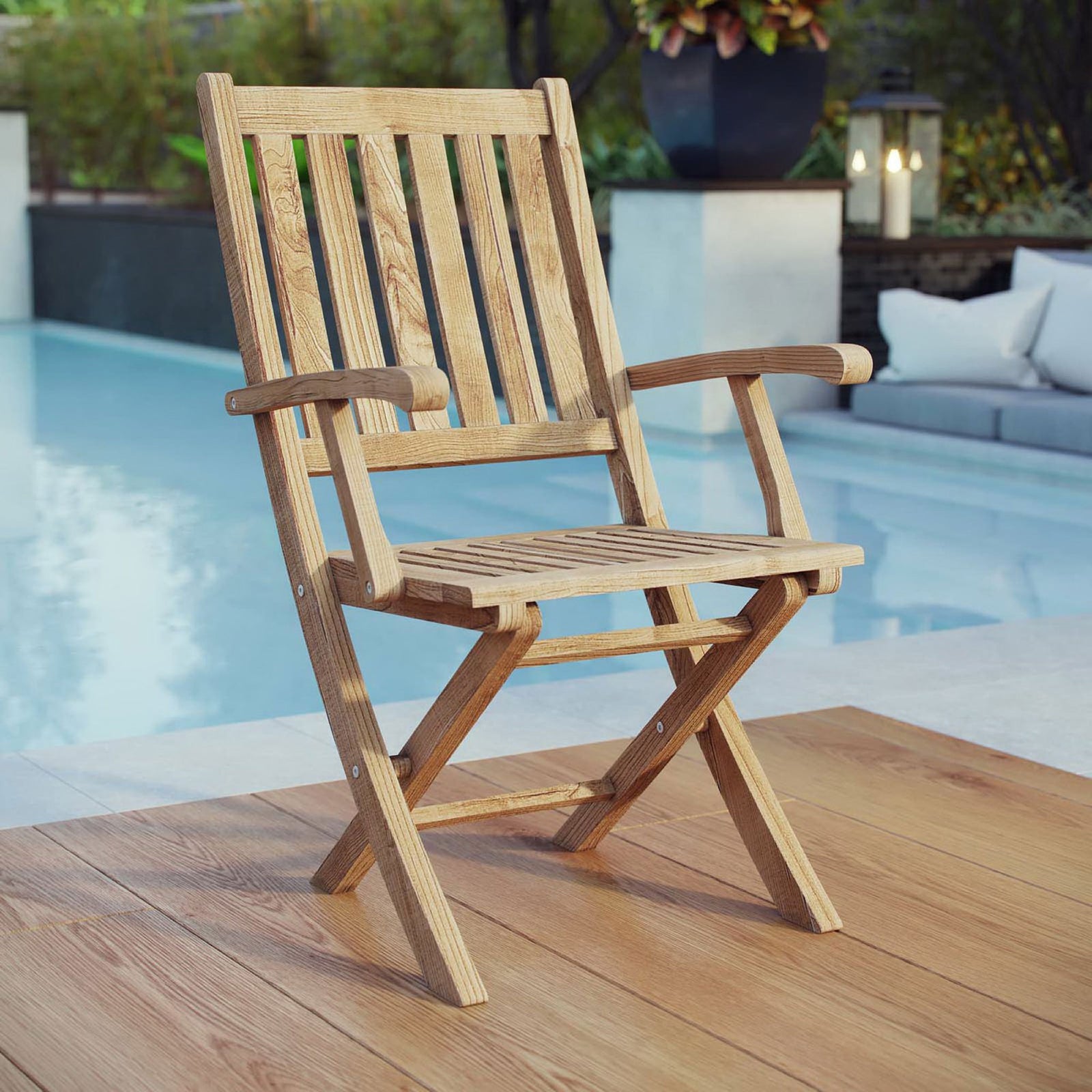 Teak folding armchair styled on a poolside deck, ready for relaxed outdoor lounging || EEI-2703-NAT || front_angle_room