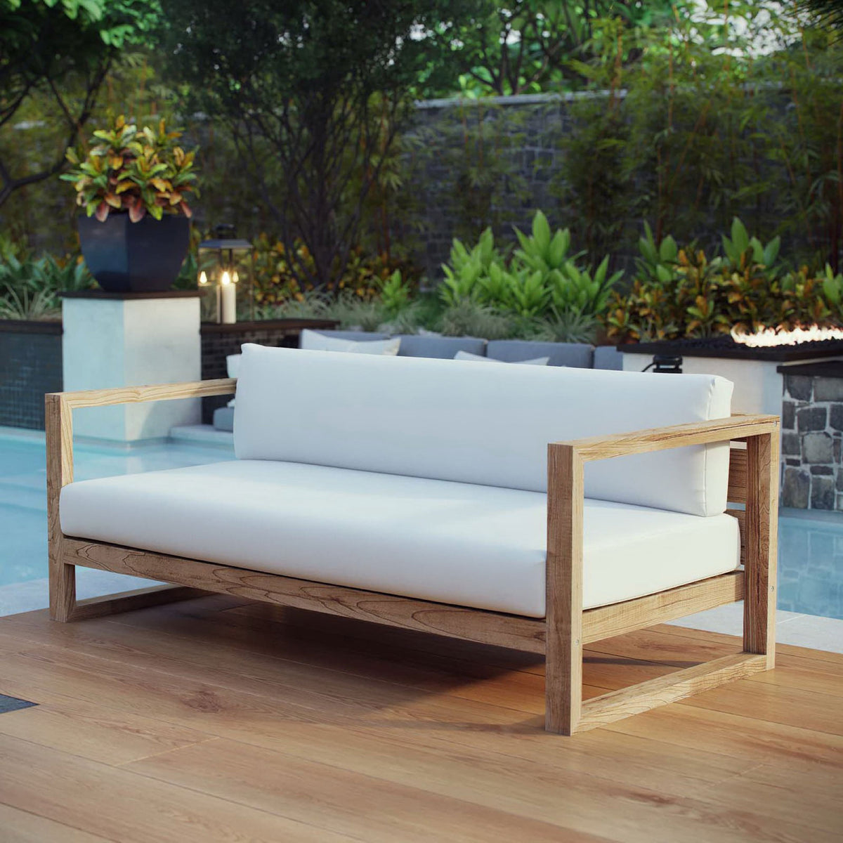 Teak outdoor sofa with white cushions placed beside a shimmering pool and lush garden || EEI-2707-NAT-WHI || front_angle_room