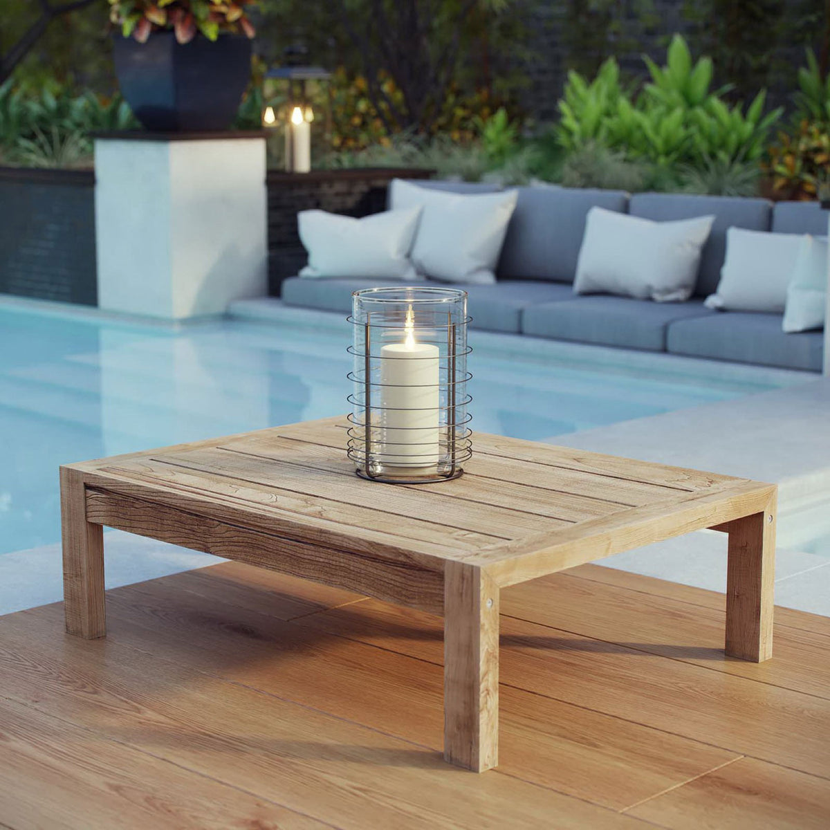 Teak outdoor coffee table styled by the pool with a candle lantern, adding warm natural texture to modern seating || EEI-2710-NAT || front_angle_room