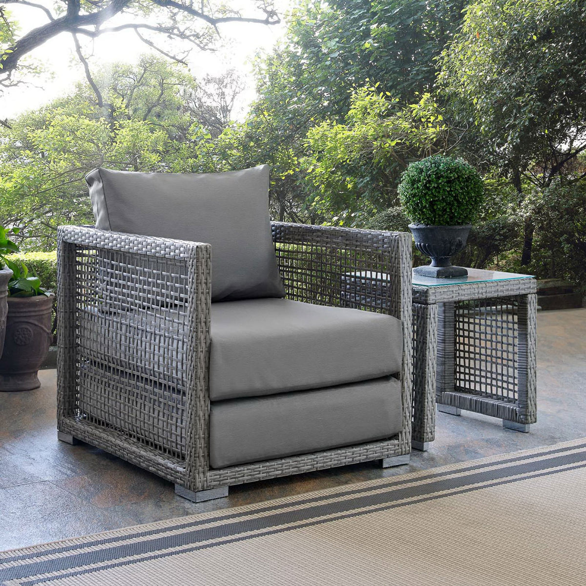 Gray Aura patio armchair styled on an outdoor terrace with matching side table for inviting lounge seating || EEI-2918-GRY-GRY || front_angle_room