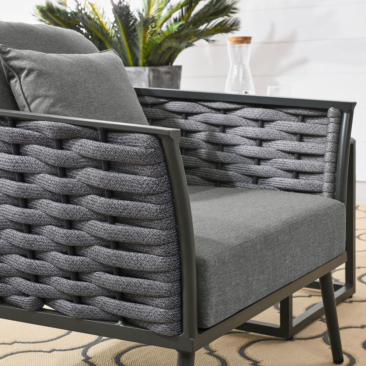 Textured gray rope weave and plush cushions of the Stance outdoor armchair on the patio || EEI-3054-GRY-CHA || detail_room