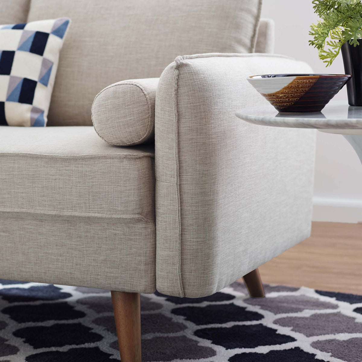 Textured beige fabric and a matching cylindrical bolster soften the loveseat's gently angled arm.