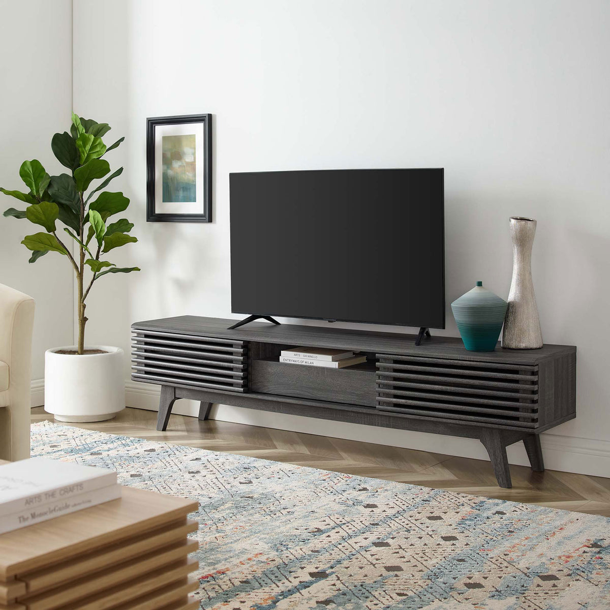 Charcoal TV stand styled in a modern living room with TV, rug, and decor accents || EEI-3305-CHA || front_angle_room