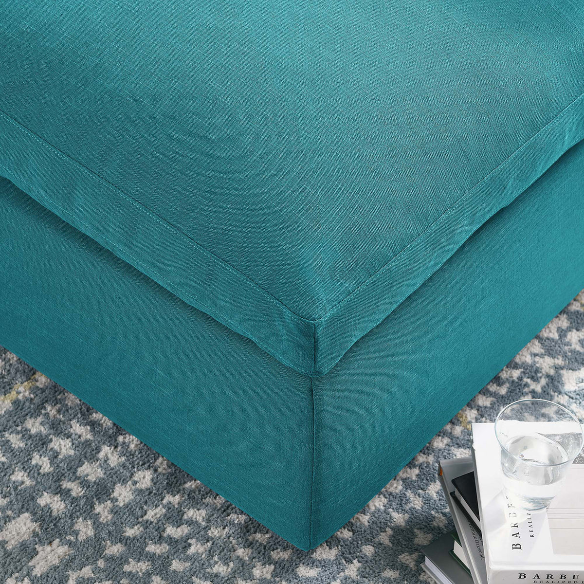 Stitched edges define the plush teal cushion and its smooth upholstered base
