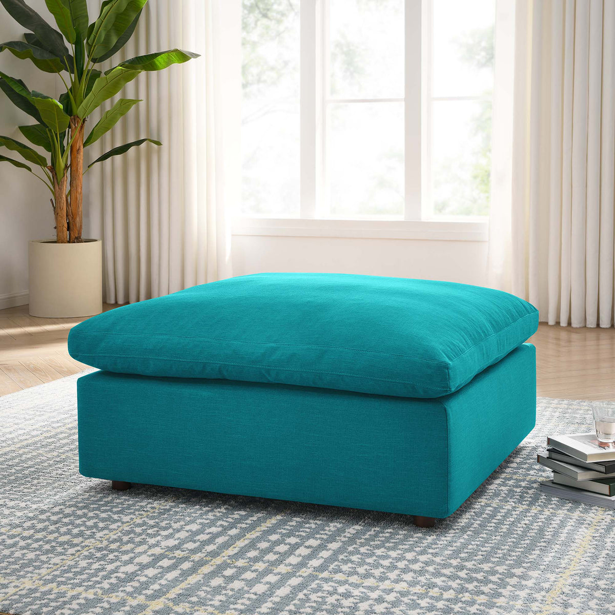 An oversized teal ottoman adds a vibrant, lounge-ready seat to a sunlit living room