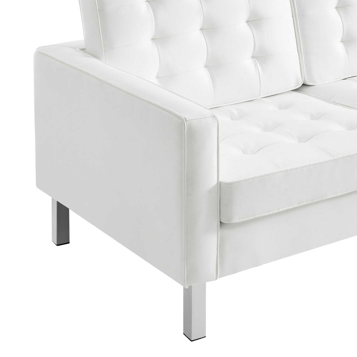 White biscuit-tufted cushions meet a squared upholstered arm above sleek metal legs.