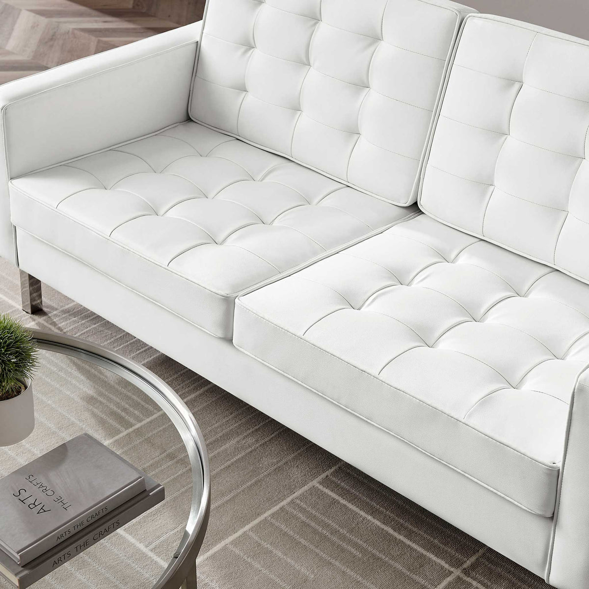 Plush white vegan leather cushions showcase biscuit tufting across the seat and supportive back.