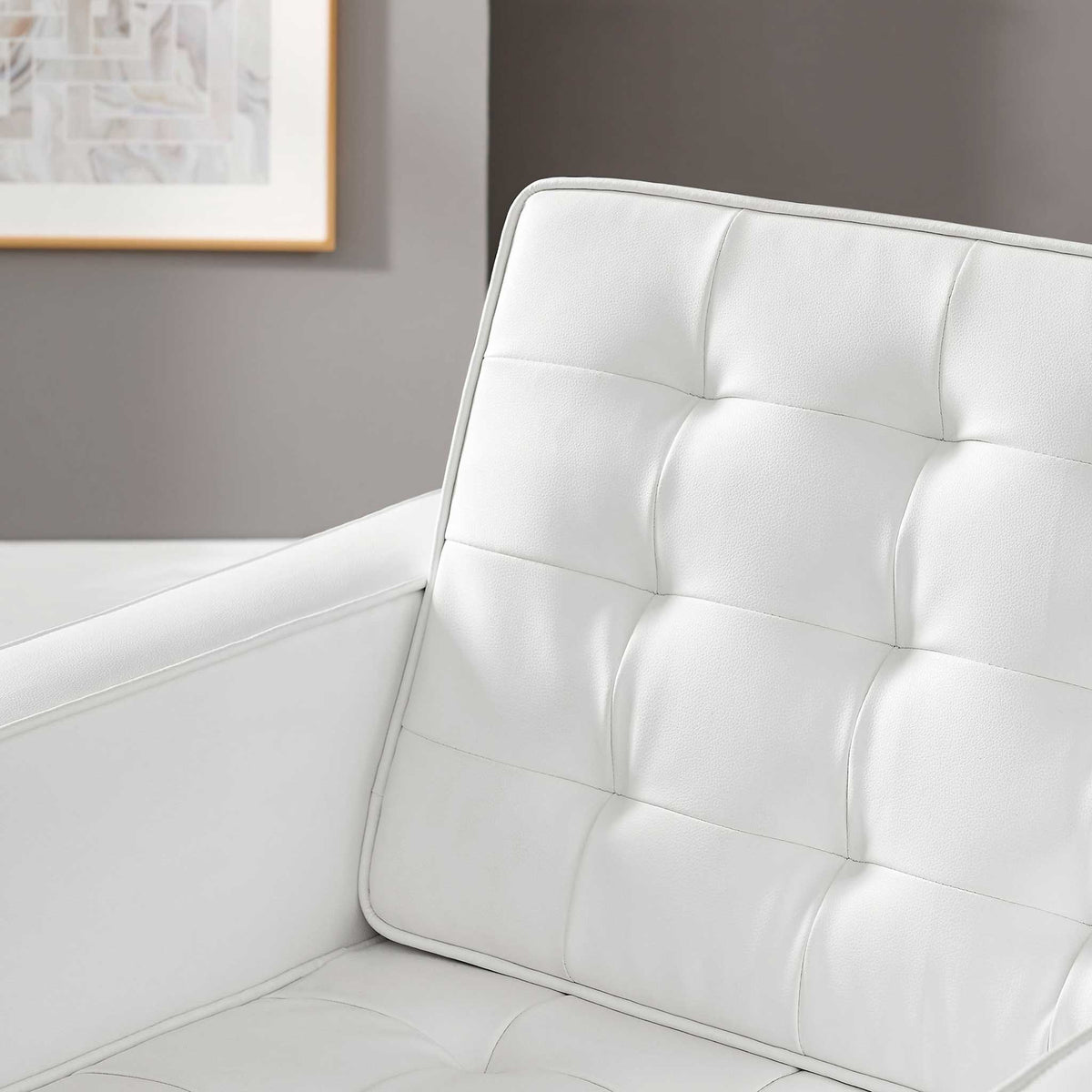 White vegan leather upholstery brings subtle texture to the chair's biscuit-tufted cushions.