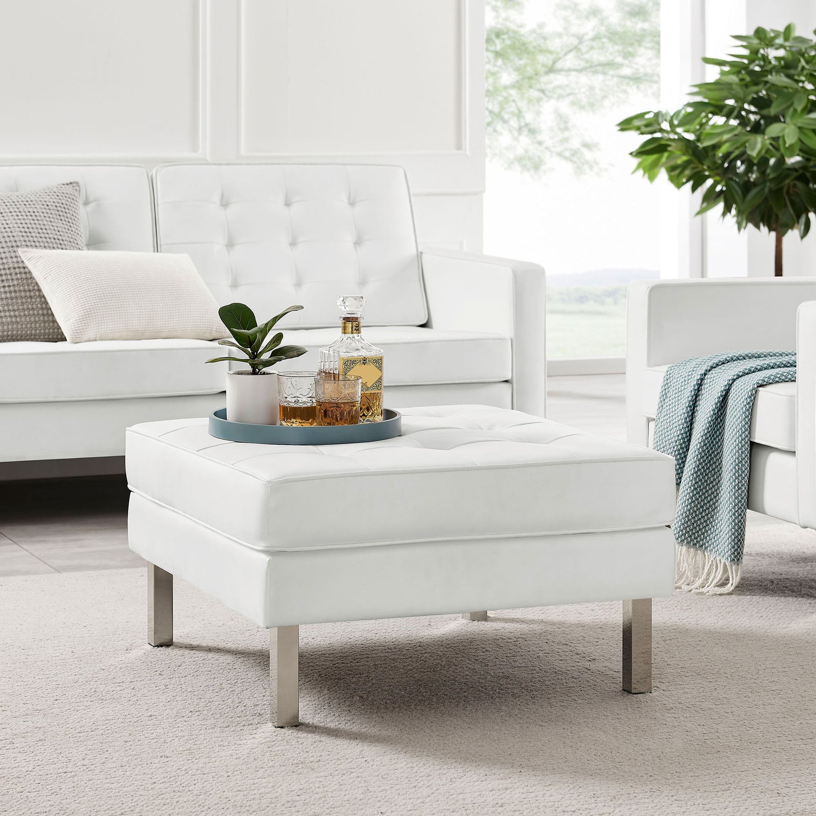 White tufted ottoman styled in a bright living room with matching sofa and a tray for drinks || EEI-3394-SLV-WHI || front_angle_room