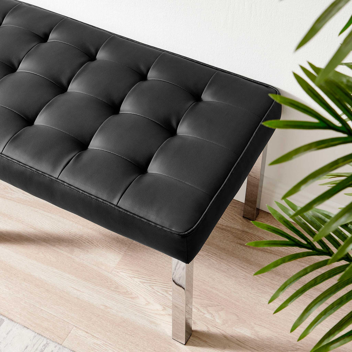 Plush black tufting meets a polished silver leg for a crisp, modern finish