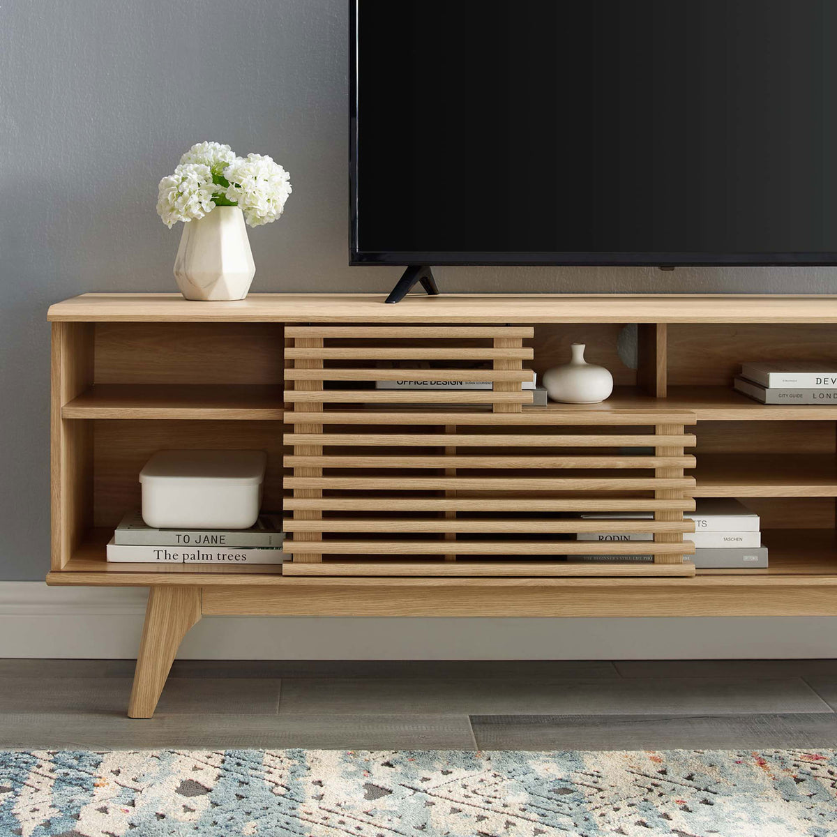 Oak media console shelving styled with books and decor beside a TV in a contemporary room || EEI-3433-OAK || detail_room