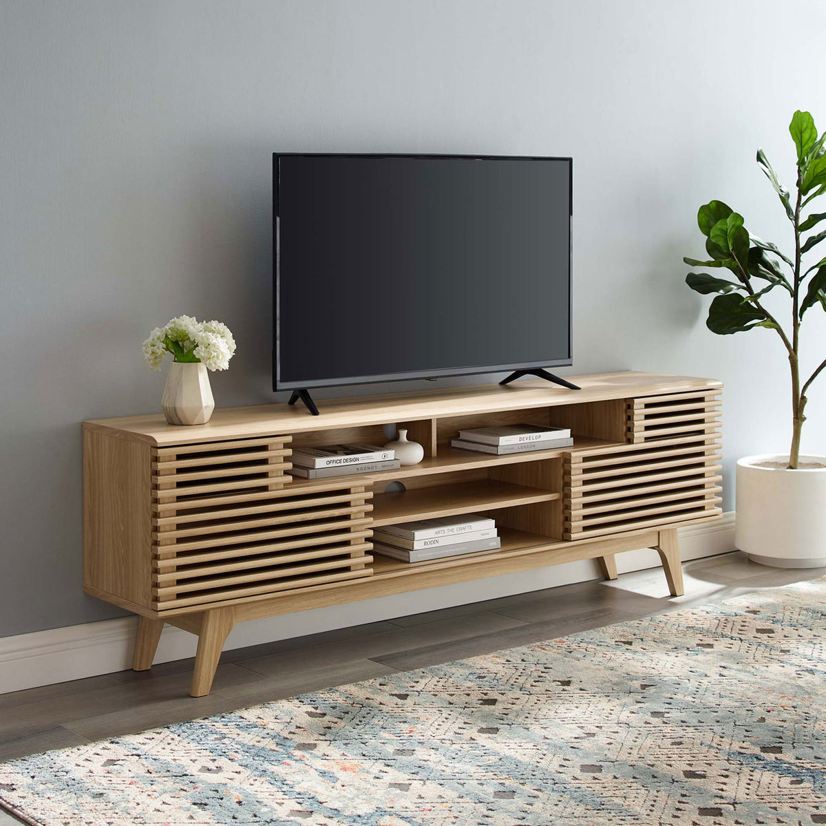 Oak media console styled in a modern living room with TV, rug, and greenery || EEI-3433-OAK || front_angle_room