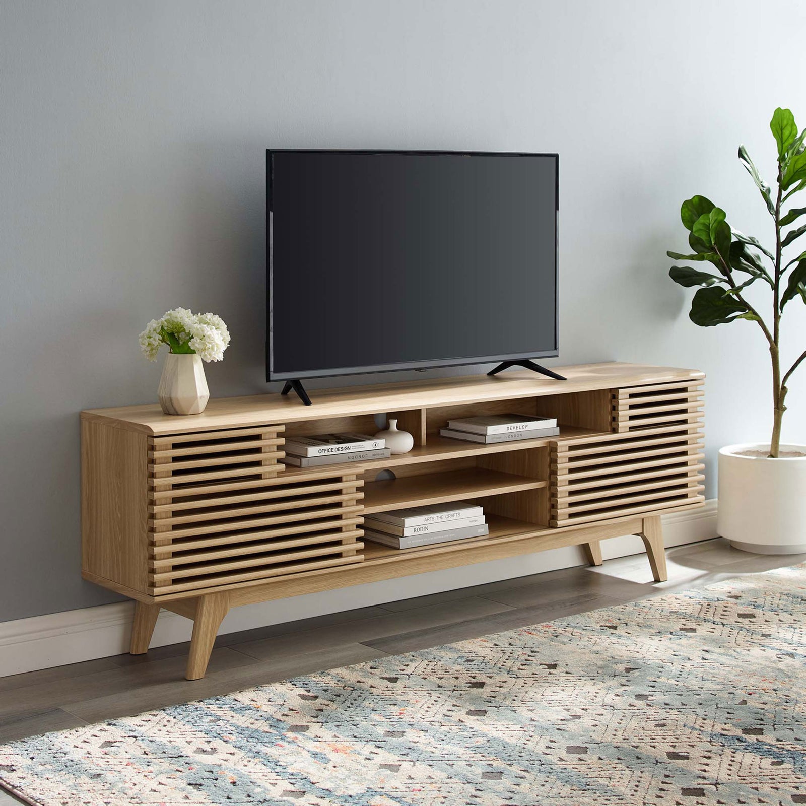 Oak media console styled in a modern living room with TV, rug, and greenery || EEI-3433-OAK || front_angle_room