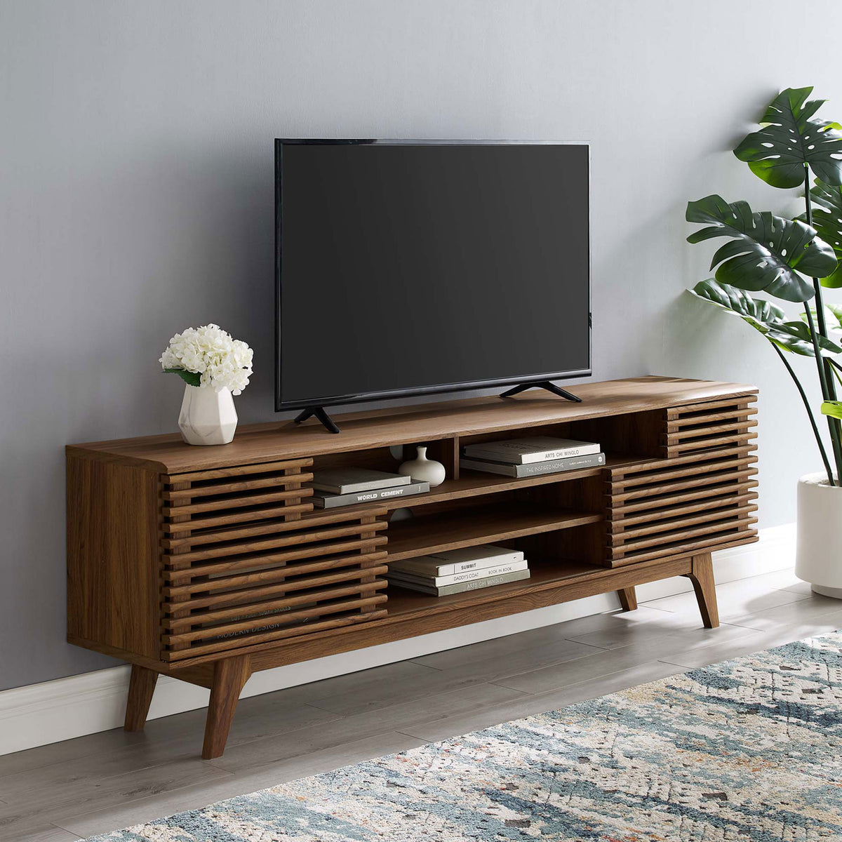 Walnut media console in a styled living room with TV, rug, and plant decor || EEI-3433-WAL || front_angle_room