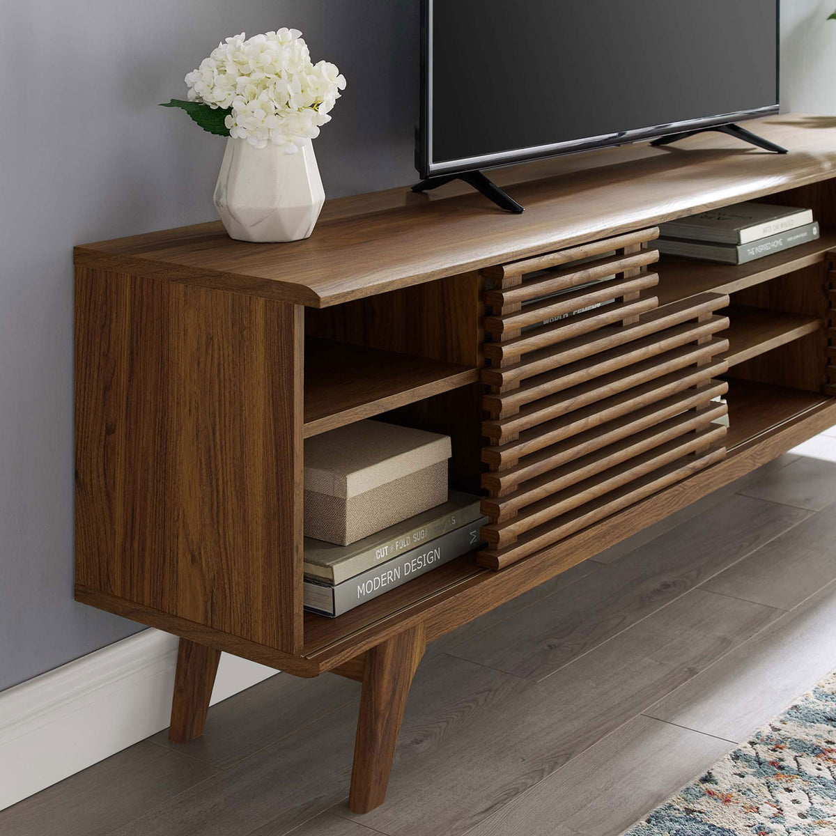Walnut media console shelving arranged with books and decor next to a television || EEI-3433-WAL || detail_room