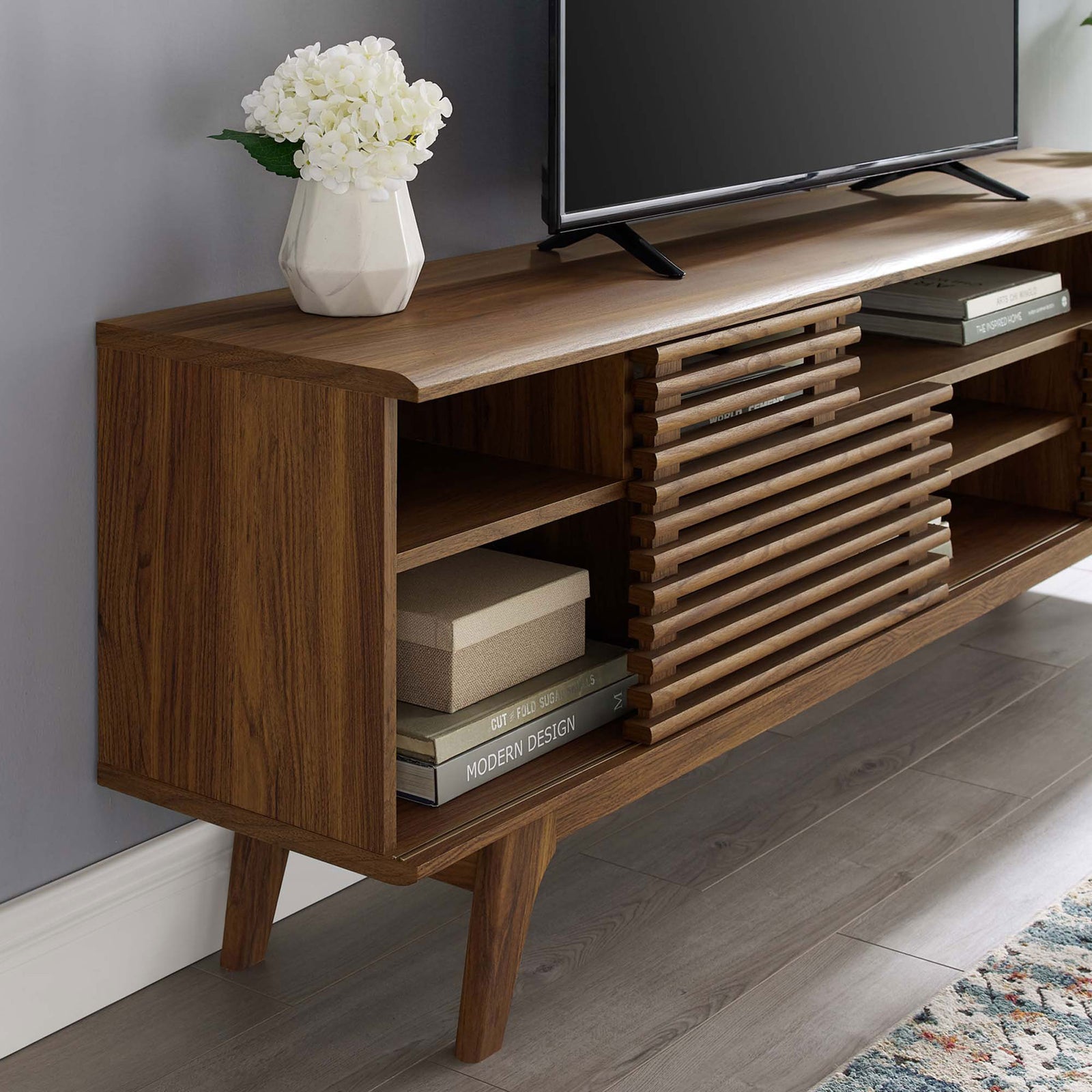 Walnut media console shelving arranged with books and decor next to a television || EEI-3433-WAL || detail_room