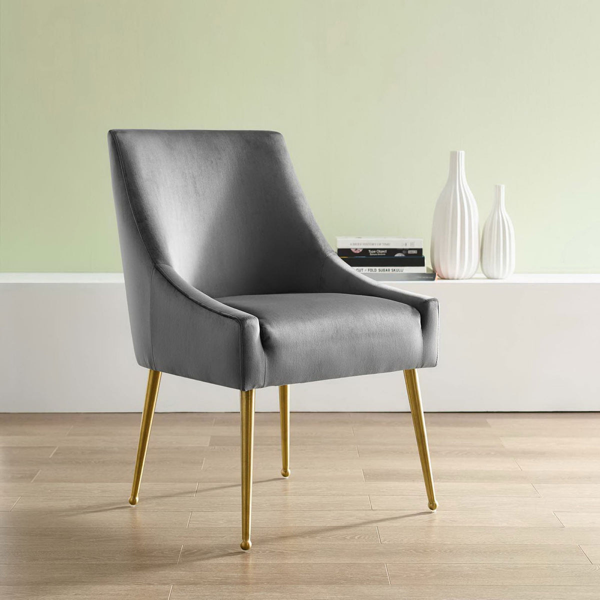 Gray velvet dining chair with gold legs styled in a modern room beside white ceramic vases. || EEI-3508-GRY || front_angle_room