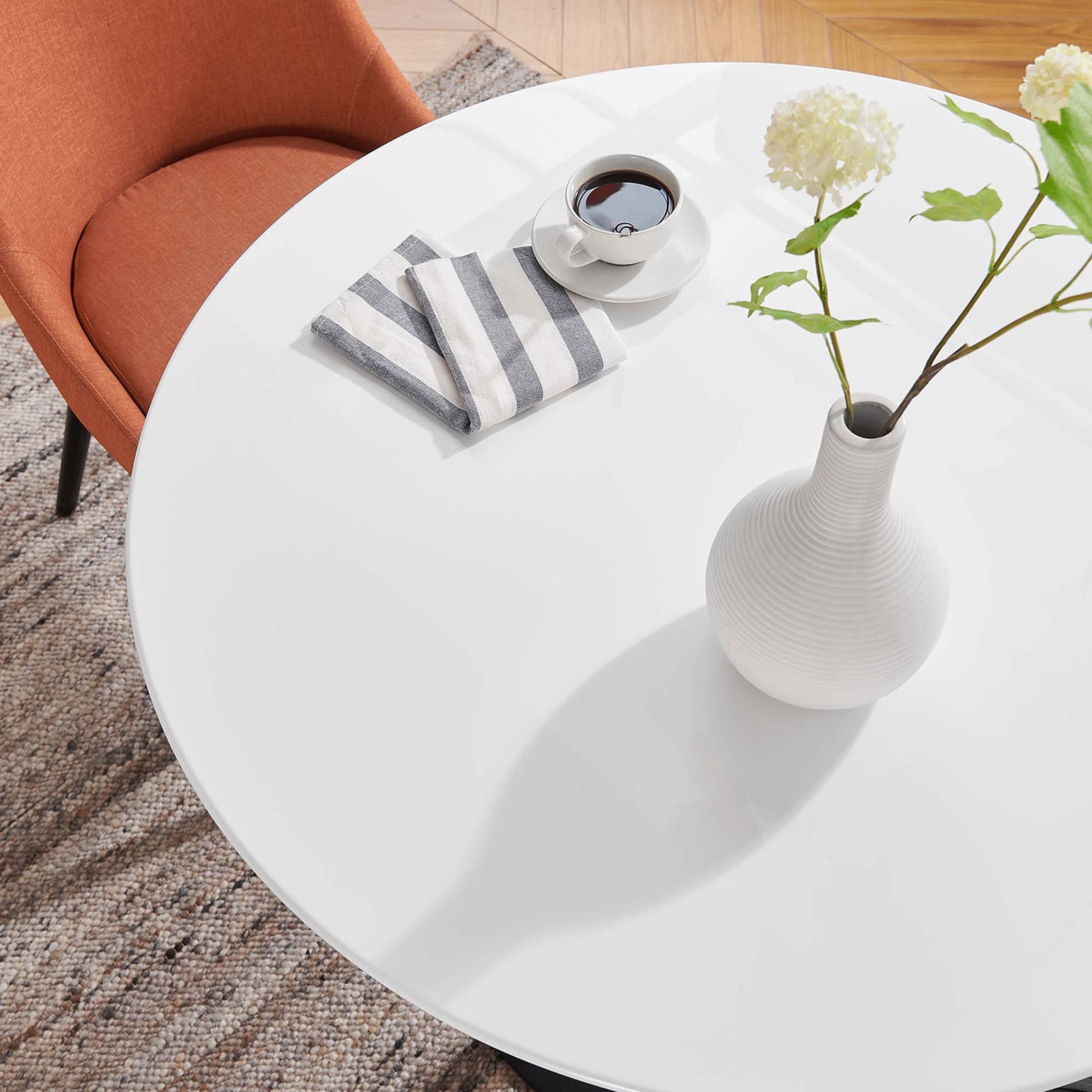 Close-up of glossy white tabletop styled with vase, coffee, and striped napkin in cozy dining nook || EEI-3511-BLK-WHI || detail_room
