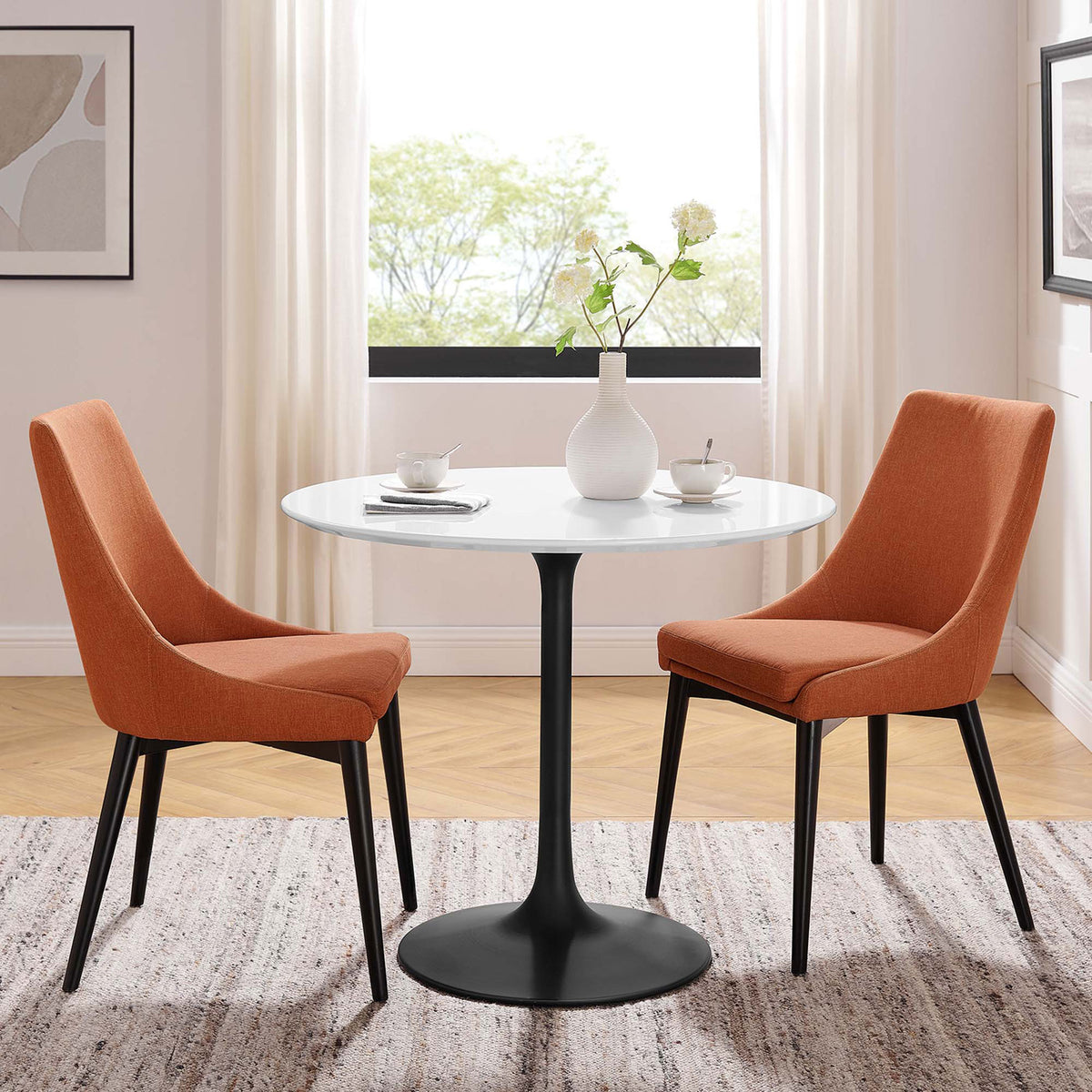 Modern round pedestal table paired with two orange chairs creates an inviting small-space dining set || EEI-3511-BLK-WHI || front_angle_room