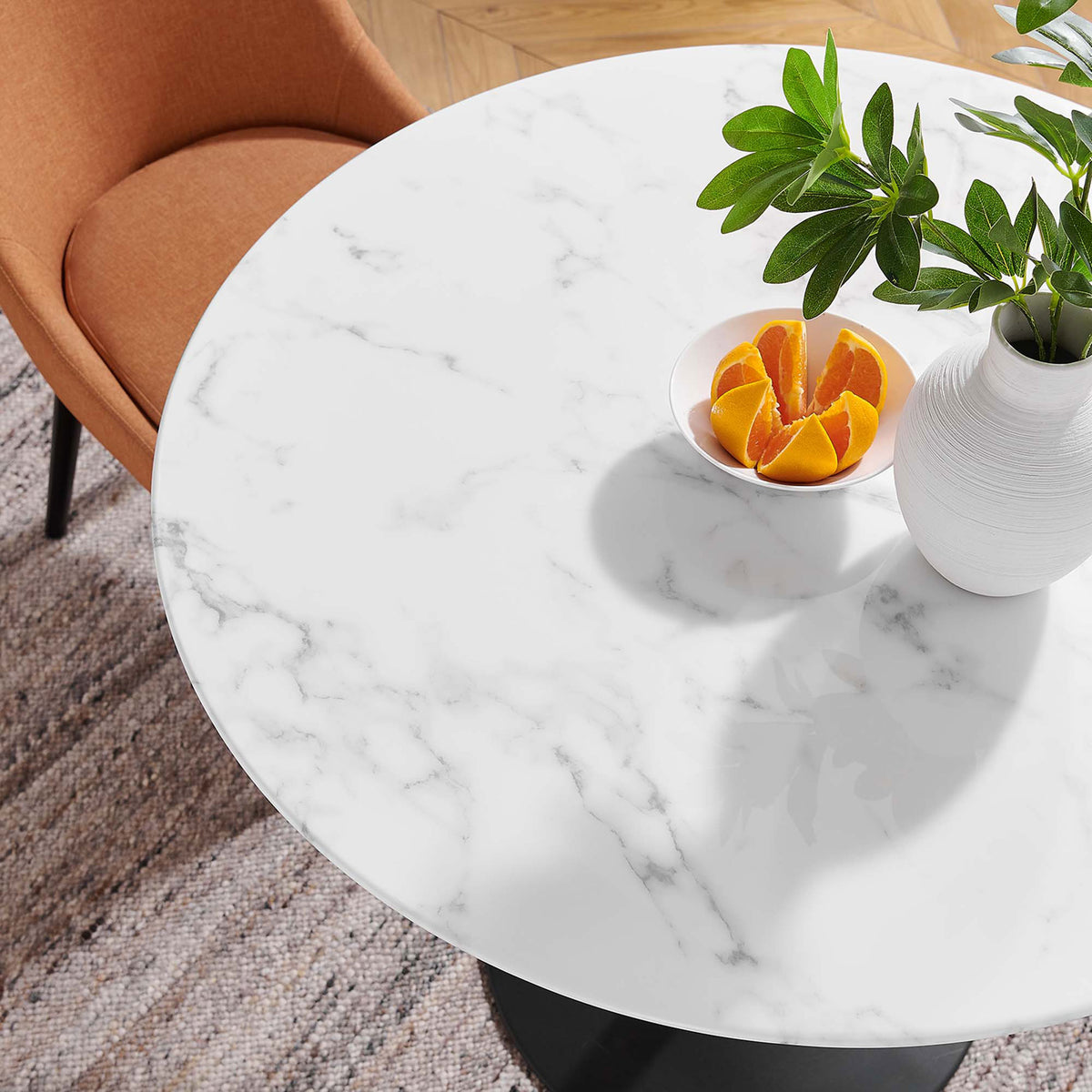 Close up of 36 inch round faux marble tabletop styled with citrus and greenery on a textured rug || EEI-3516-BLK-WHI || detail_room