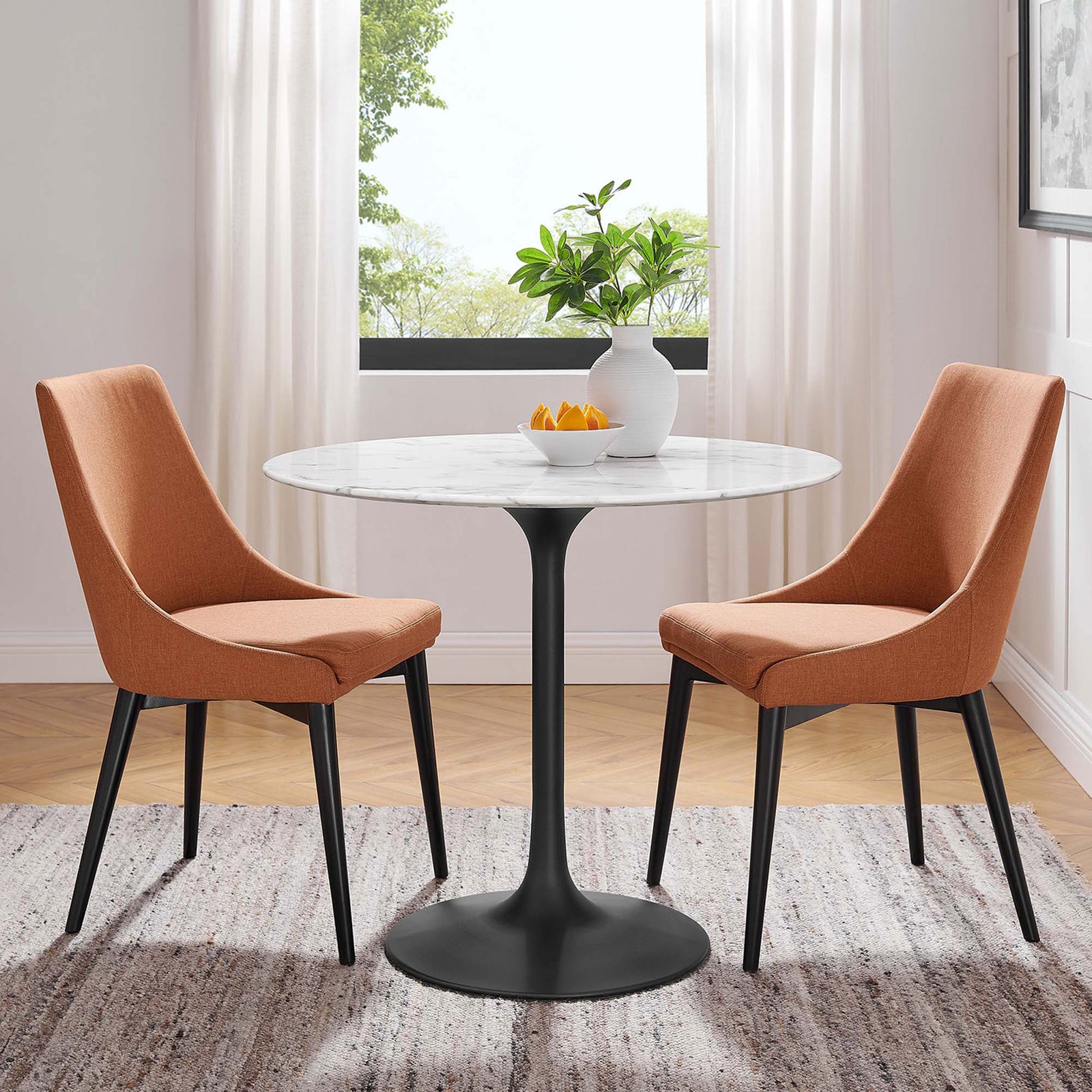 36 inch round faux marble bistro table styled with two orange upholstered chairs in a bright dining nook || EEI-3516-BLK-WHI || front_angle_room