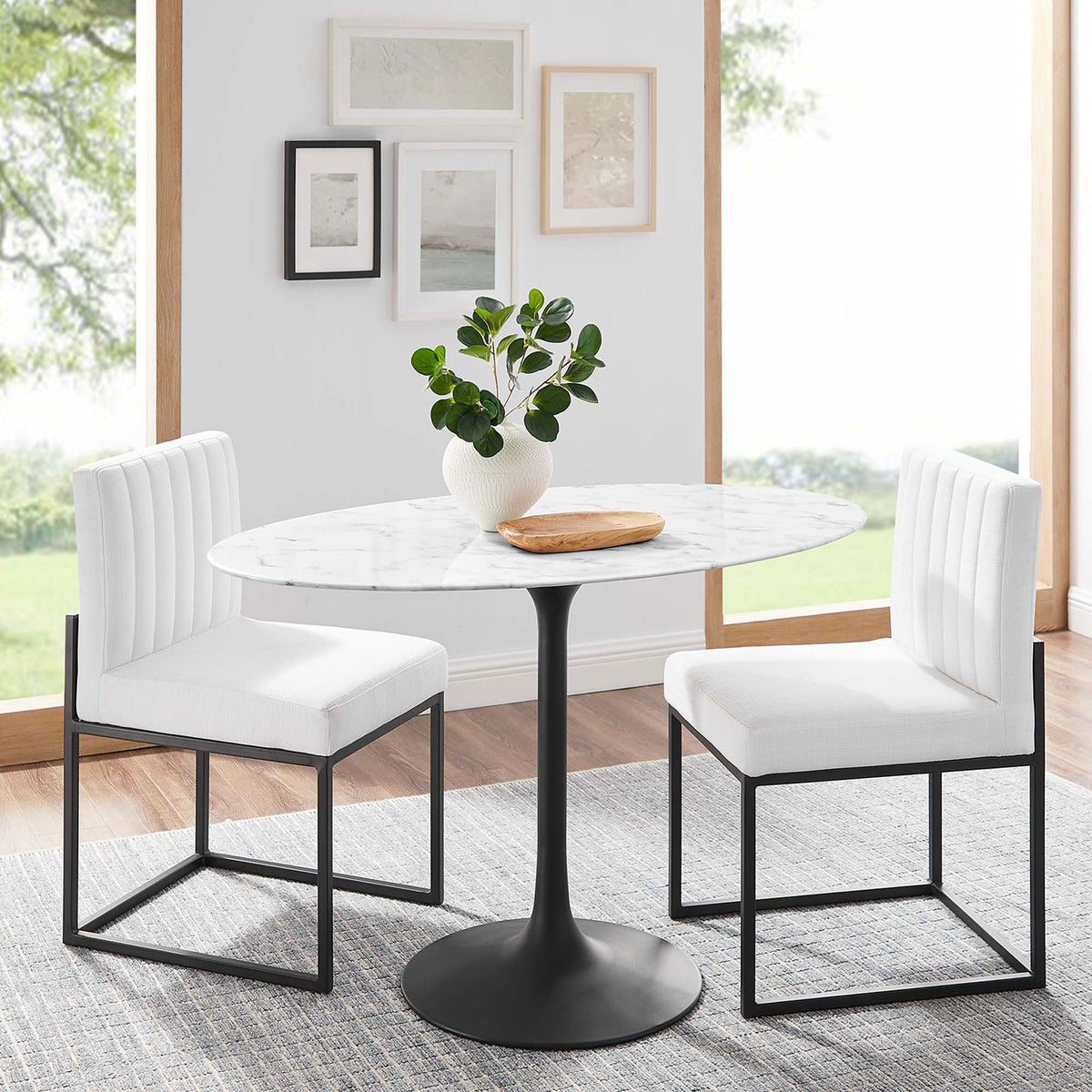 Lippa 48 inch oval faux marble dining table with black pedestal base styled in a light filled modern dining room || EEI-3518-BLK-WHI || front_angle_room