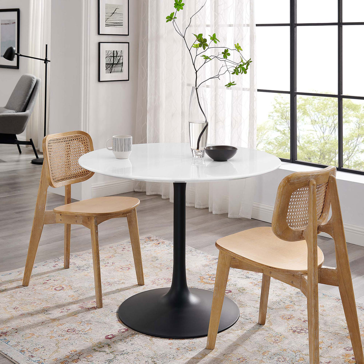 Scandinavian-inspired dining scene with round pedestal table and two natural wood chairs || EEI-3521-BLK-WHI || front_angle_room