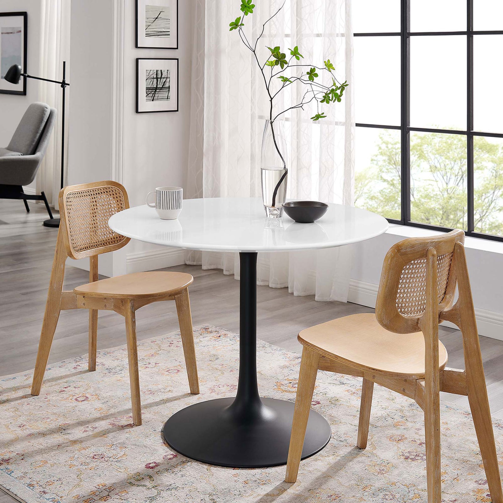 Scandinavian-inspired dining scene with round pedestal table and two natural wood chairs || EEI-3521-BLK-WHI || front_angle_room