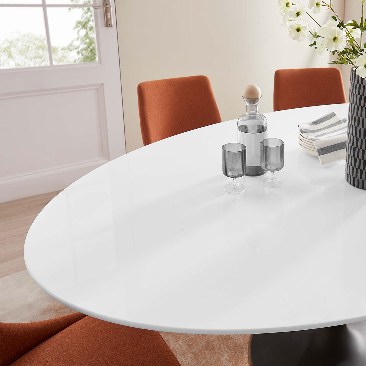 Glossy white tabletop paired with warm upholstered chairs and decor for an inviting modern dining setting || EEI-3540-BLK-WHI || detail_room