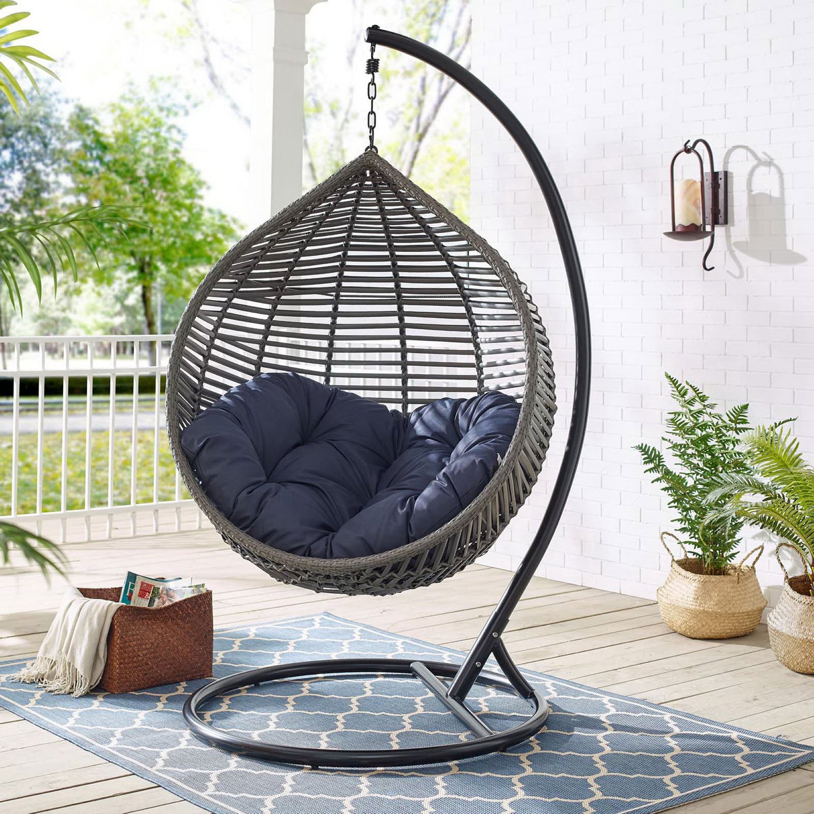 Teardrop swing chair with navy cushion and stand creating a cozy lounge spot on the porch. || EEI-3614-GRY-NAV || front_angle_room