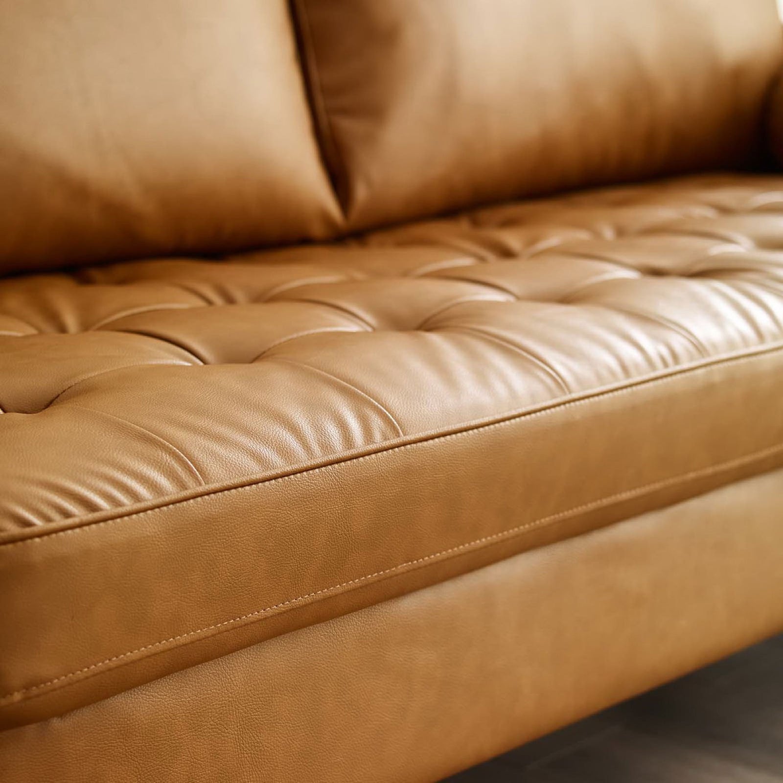 Detailed view of tufted tan seat cushion and front rail of the Valour vegan leather sofa || EEI-3765-TAN || detail_room